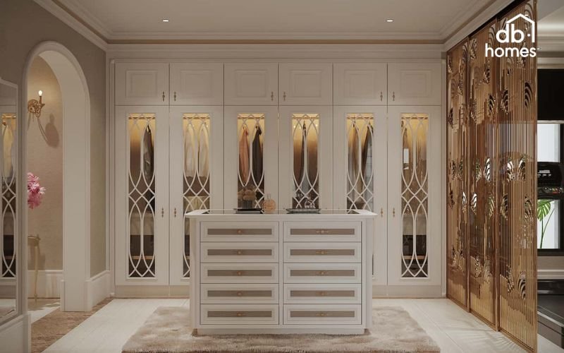 Phòng thay đồ sang trọng với tủ trắng kem, kính họa tiết cổ điển và vách ngăn ánh vàng đẳng cấp